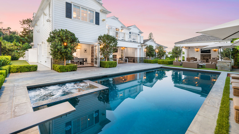 A large swimming pool in the backyard of a grand home.