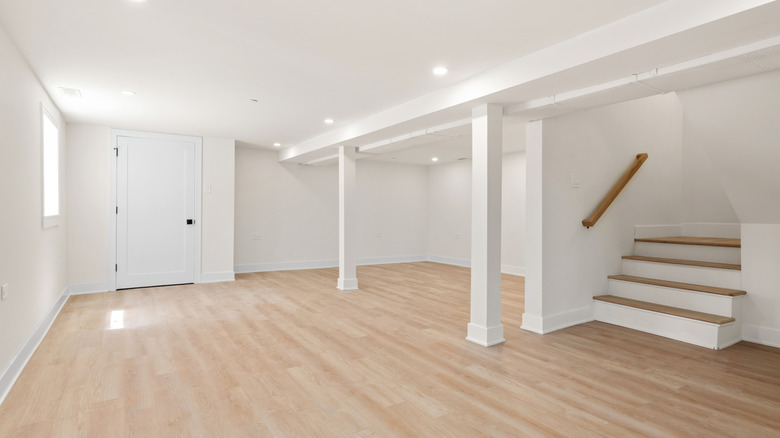 An empty, finished basement with hardwood floors.
