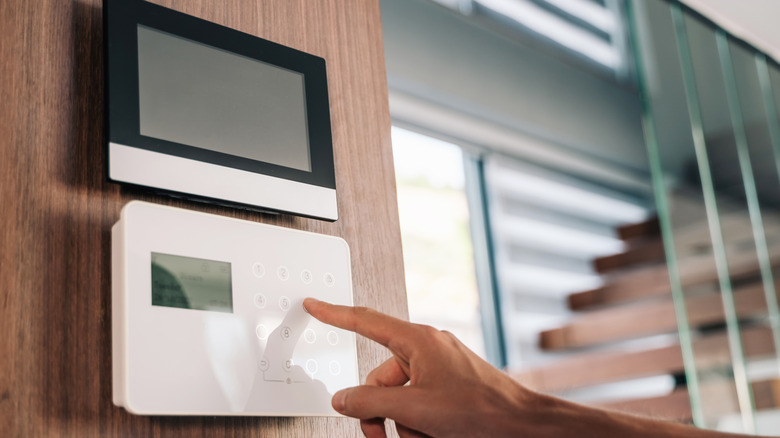 A finger pressing a code into a home security system.
