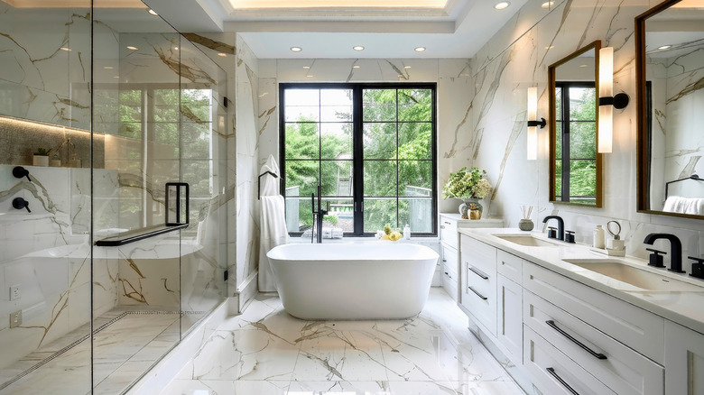 A marble tiled bathroom with modern black fixtures and a free standing tub.