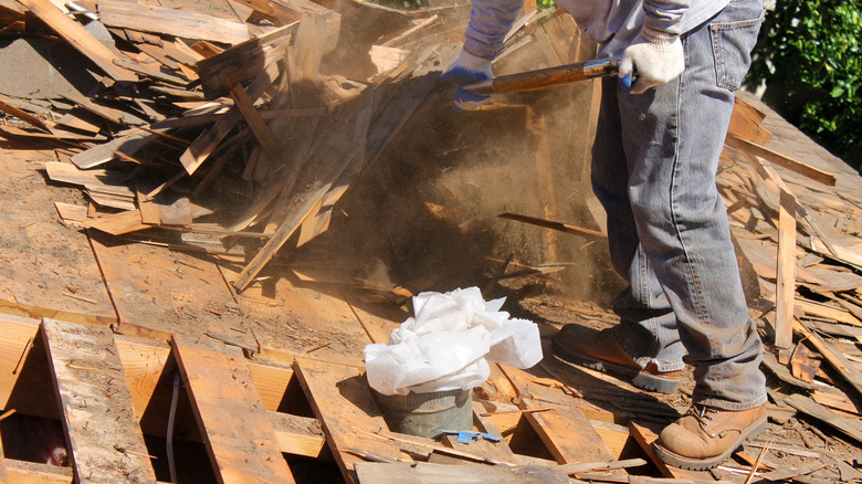 A contractor stands on top of a demolished roof