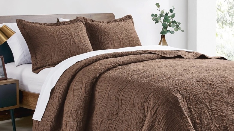 A brown quilt with a coin pattern on a bed