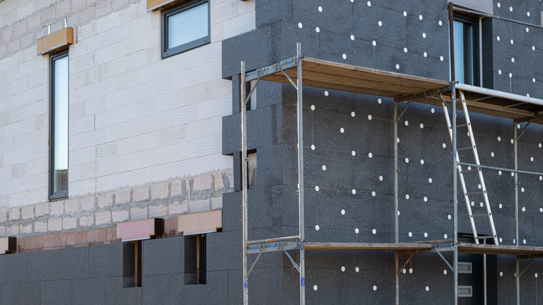 New House building in process insulation of the wall of the house with layers of modern thermal insulation materials . Exterior covering in construction site.