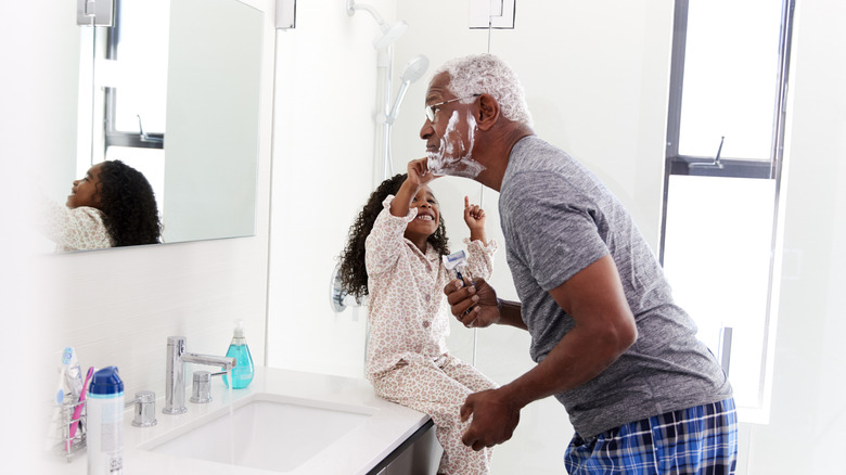 Granddaughter helping grandfather shave his beard