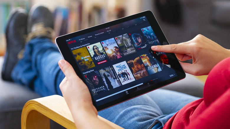 A relaxed person is looking at titles available on Netflix
