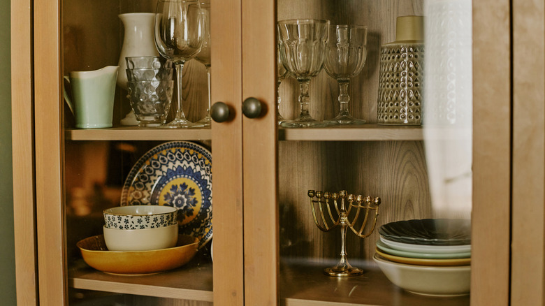 Tableware and decor for hosting at home organized inside a glass-fronted closet.