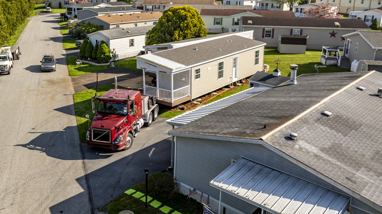 Truck delivering a modern manufactured home to land plot