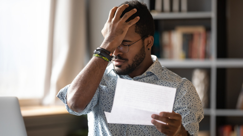 A man face palming looking at a letter.