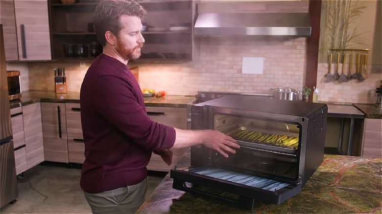 Man placing a tray of asparagus into a countertop steam oven