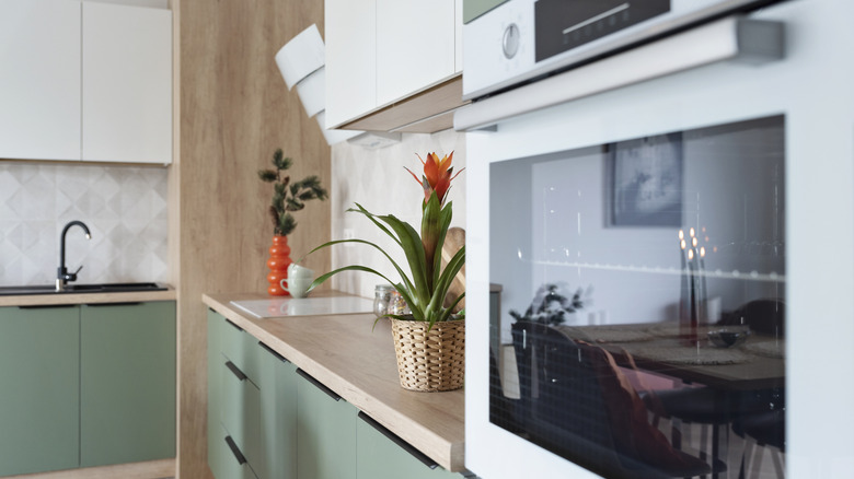 Kitchen with bamboo countertops, green lower cabinets, and wall oven.