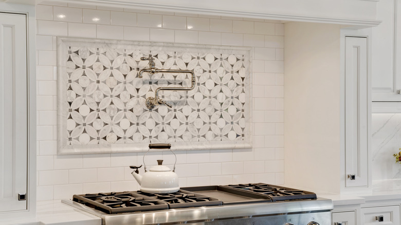 Range alcove with white and patterned tile backsplash and white kitchen cabinets