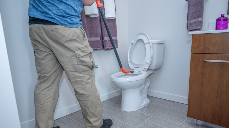 Person using a toilet auger