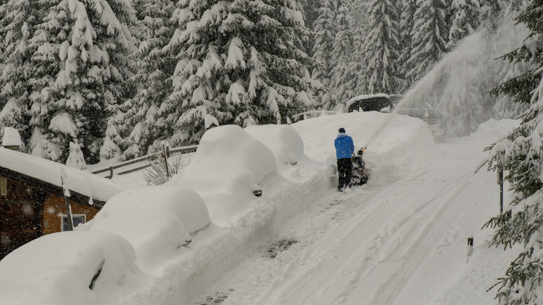 Man clearing deep snow on hill using snowblower