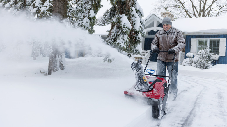 Man pushing snowblower across front yard