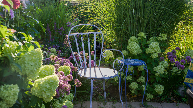 Chair and table nestled amidst plants and flowers