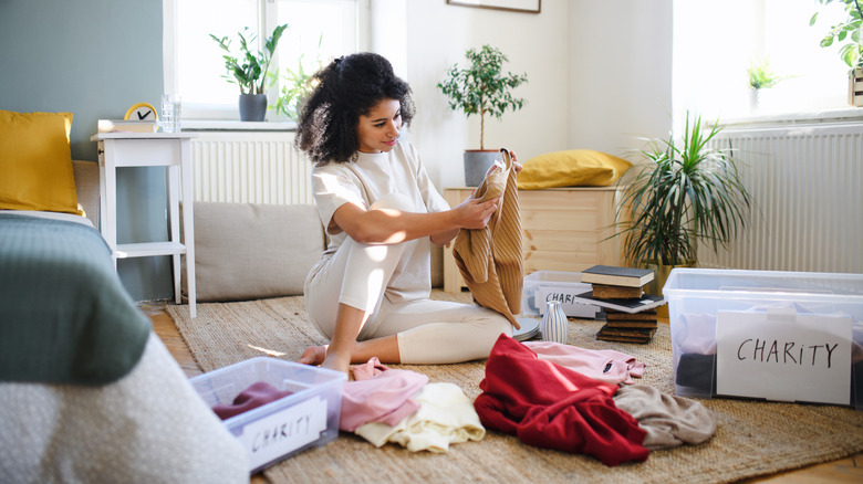 Person sitting on floor going through items to declutter