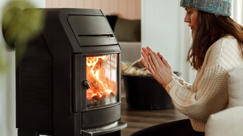 Woman warms hands in front of stove