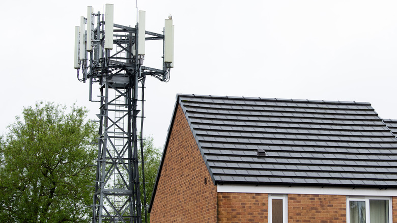 A mobile phone cell tower is next to a brick residential home