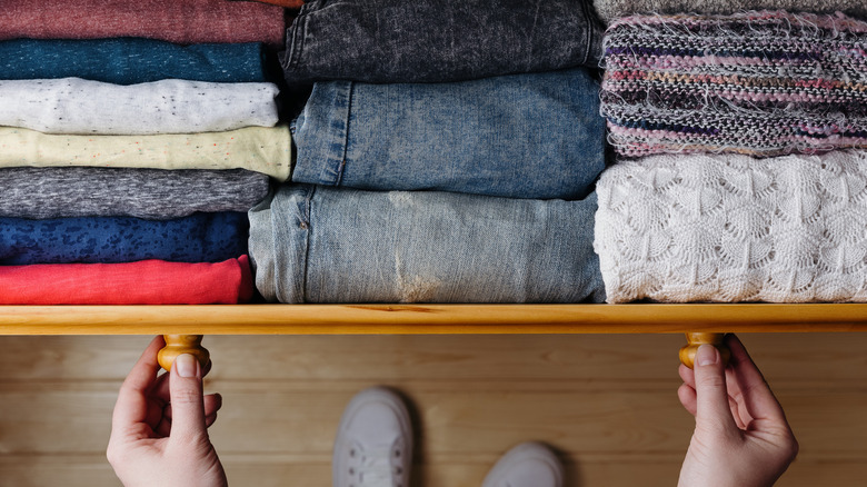 Hands opening organized clothing drawer