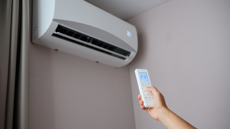 A person points a remote at an air conditioner