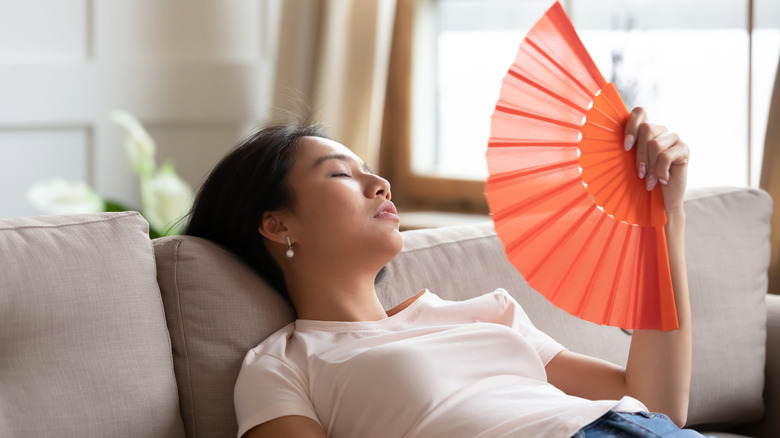Woman laying on couch and fanning herself