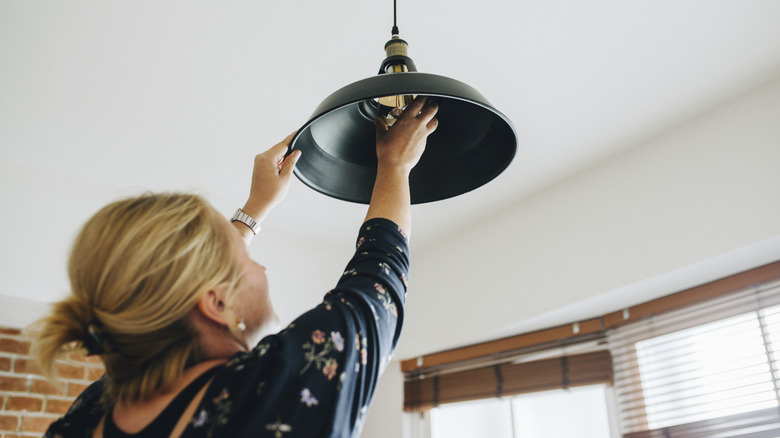 A person changing a lightbulb in a ceiling fixture
