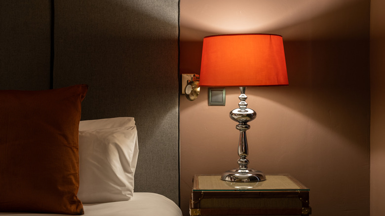 A white bulb used inside of a red lampshade on a bedside table