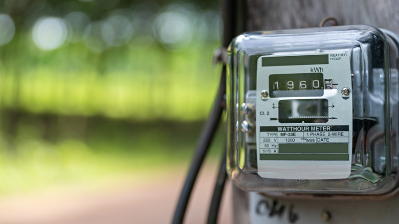 A kilowatt meter attached to a house against a blurred background