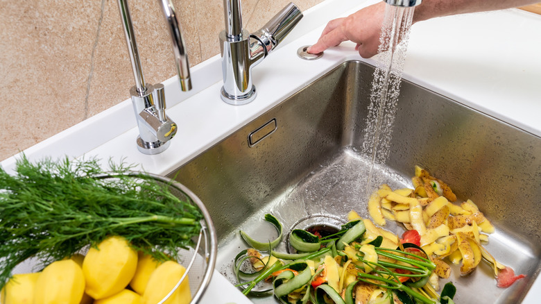 Person uses the garbage disposal to dispose of food scraps while the water is running.