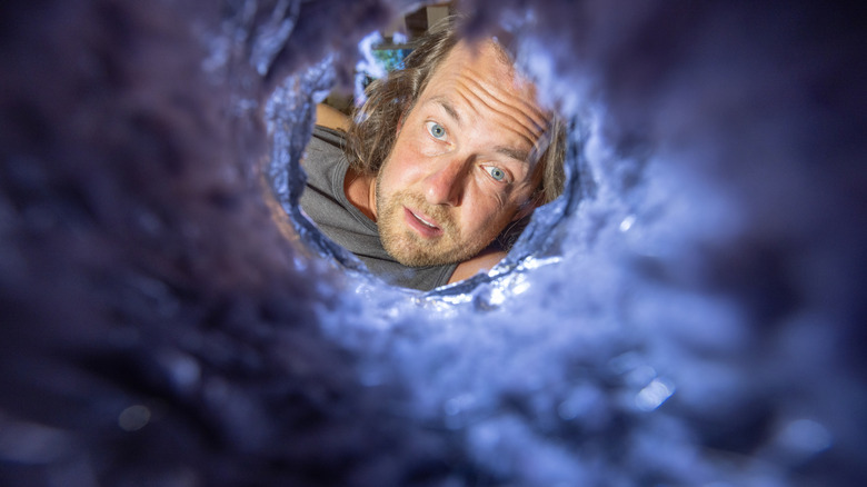 man looking through clogged vent
