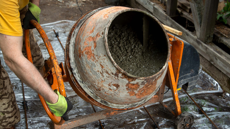 a man mixes concrete in a large orange mixer