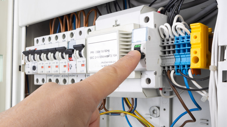 Someone switching on the main circuit breaker in a household panel
