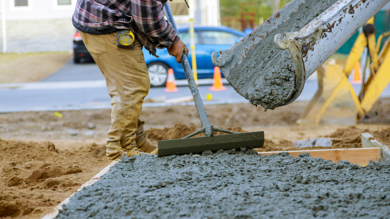 Construction worker smoothing concrete that's been poured from a cement truck.