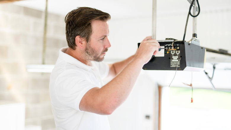 A technician in a white shirt working on a garage door opener
