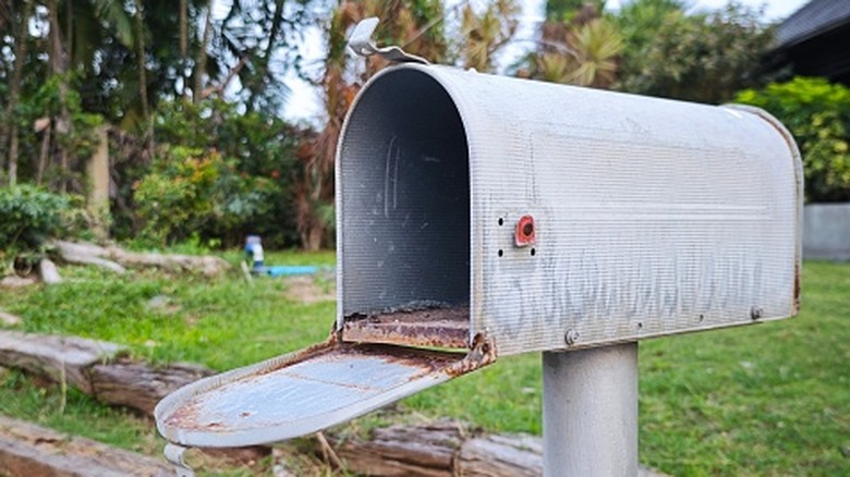 A rusted metal mailbox outside of a house
