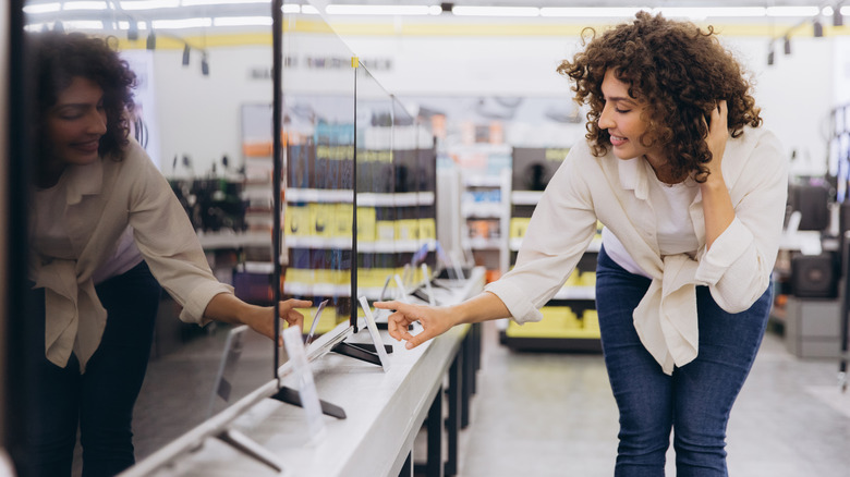 A woman shopping for a new TV in a store