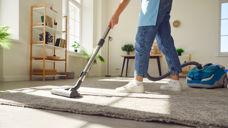 person vacuuming area rug