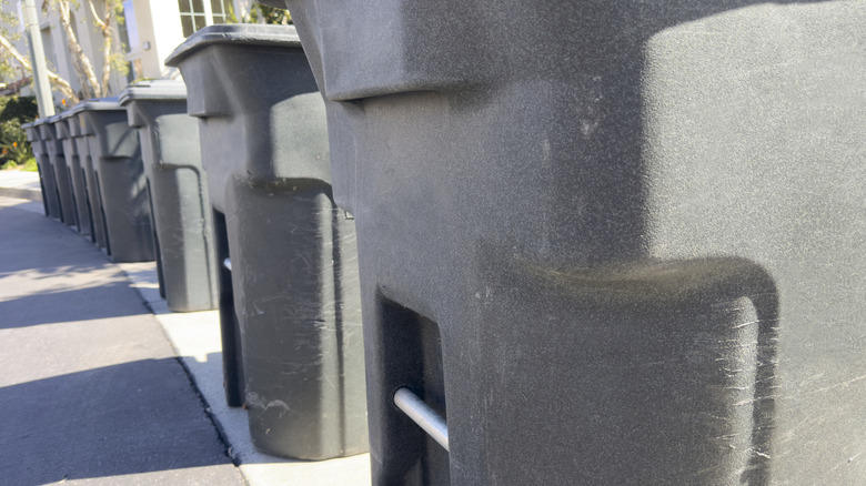 The metal bar on a garbage bin.