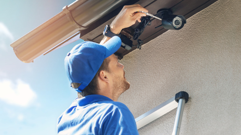 Man installs security camera on the exterior of a home