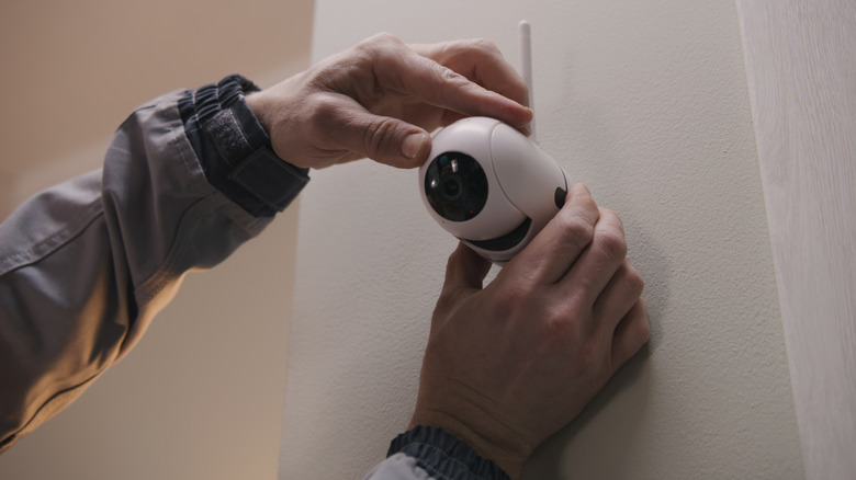 Person adjusting a wall-mounted home security camera