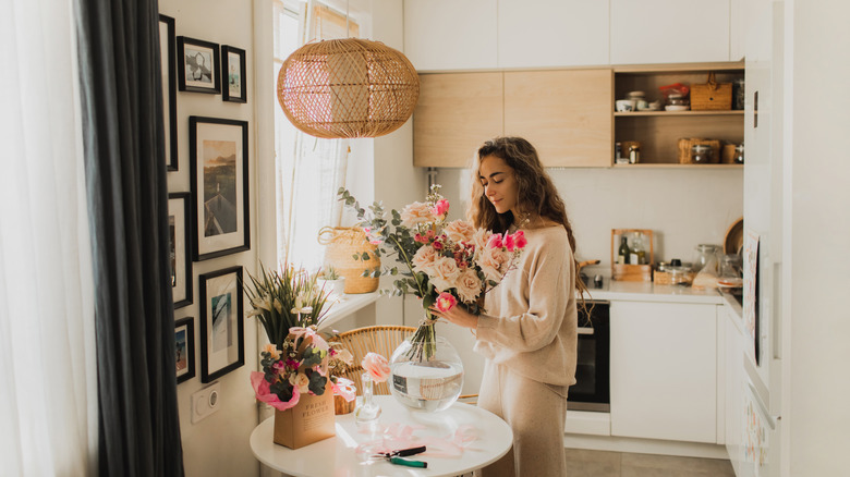 Woman trims flowers in a warm-toned kitchen