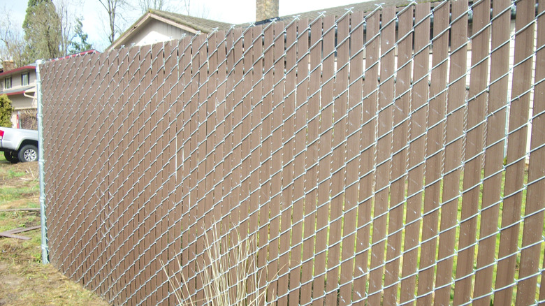 A tall chain link fence installed with privacy slats