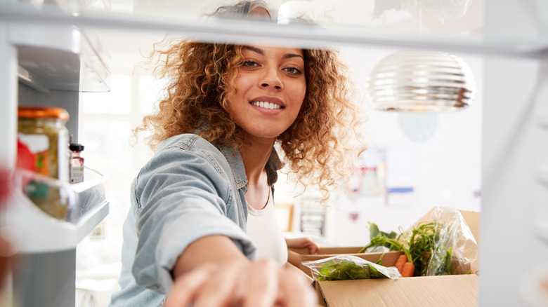 Person with arm in refrigerator