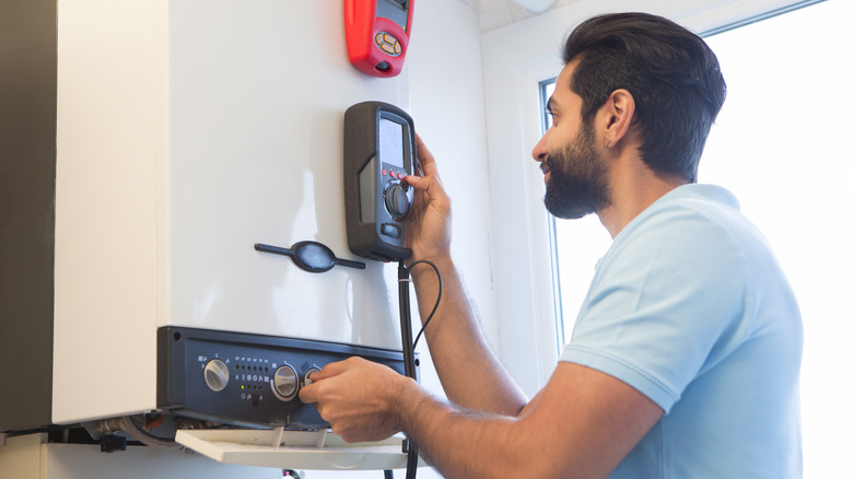 person adjusting temperature on water heater