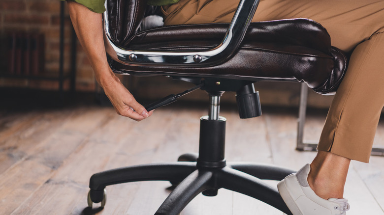 A person adjusts their office chair.
