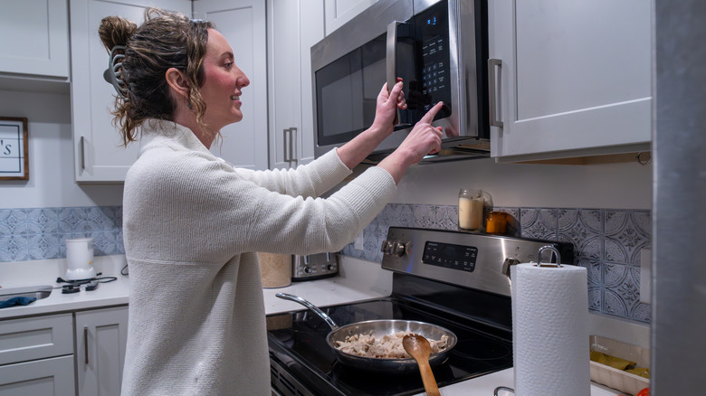 Woman cooking on a cooktop and using an over the range microwave.