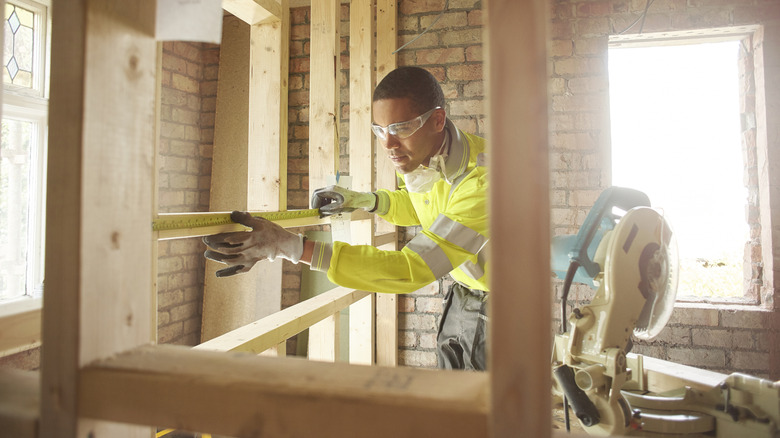 A builder measuring the distance between studs in a wall