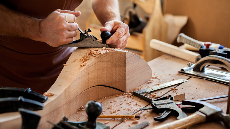 A woodworker shaping a table leg with hand tools