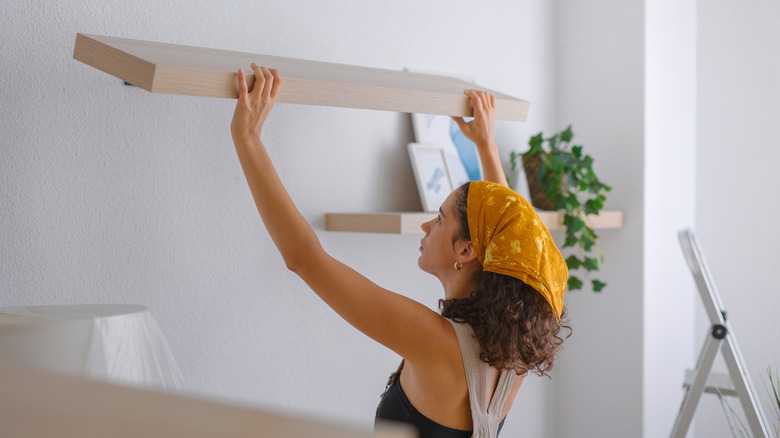Woman installing floating shelves