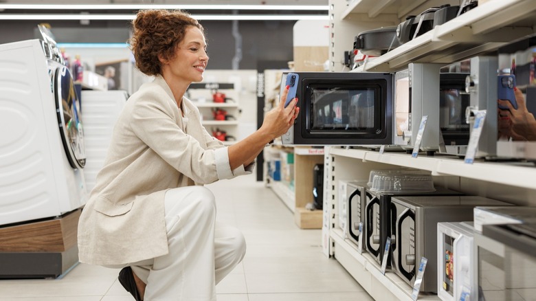 Smiling woman examining kitchen appliances in a retail store